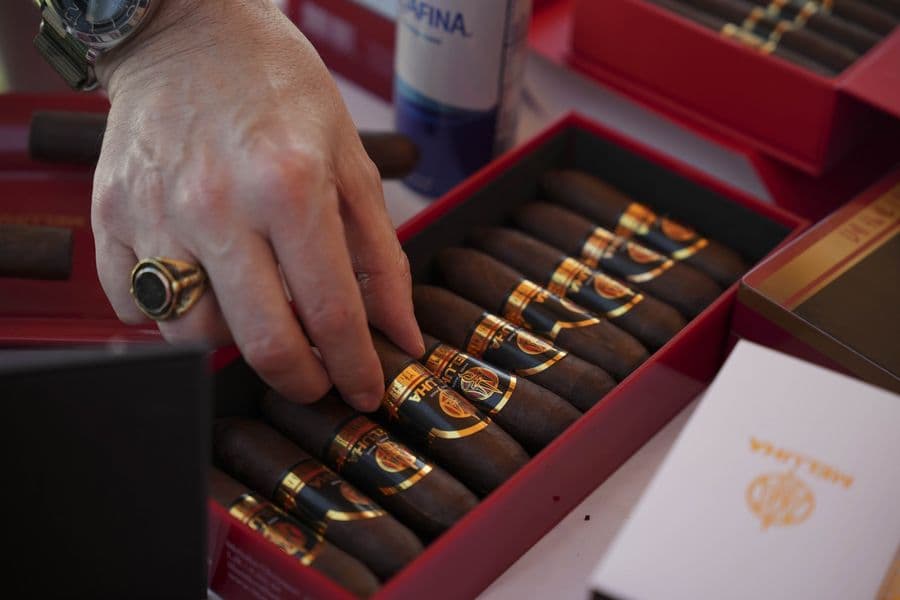 A hand selecting a cigar from a presentation box
