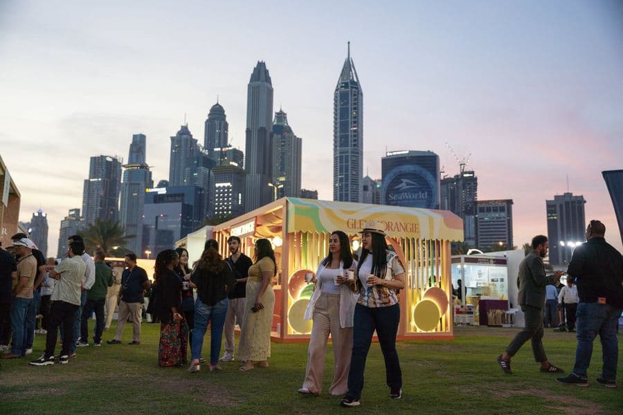 Branded whisky pavilions lit at dusk with the Dubai skyline in the distance