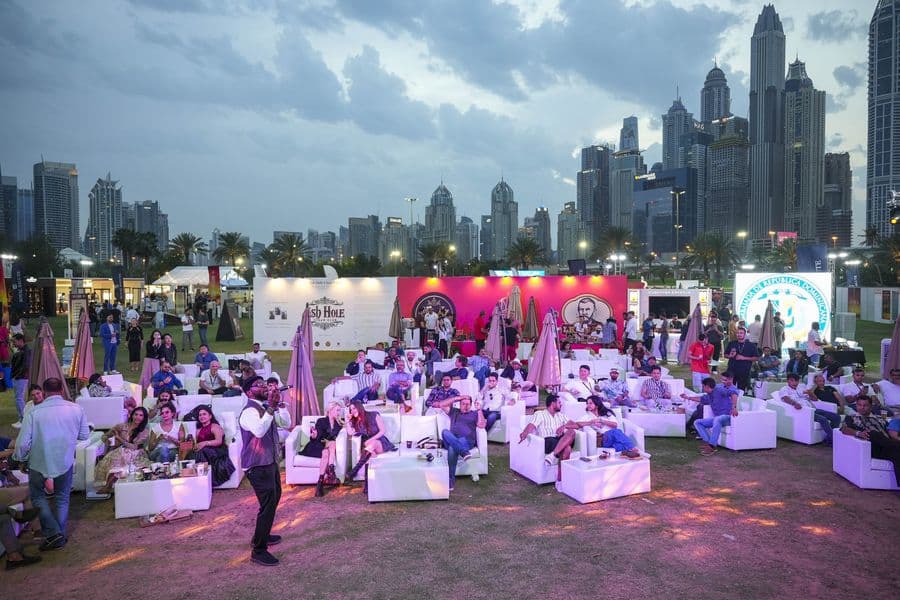 The MaltLive lawn at sunset, tables and umbrellas beneath the Marina towers