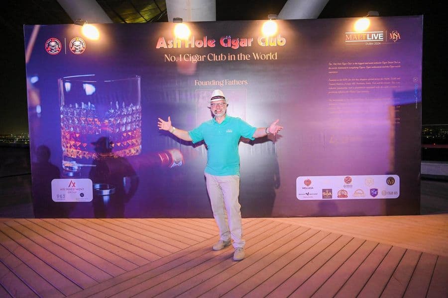 A guest in front of the Ash Hole Cigar Club backdrop