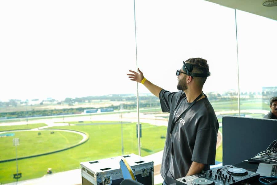 The DJ playing with the racecourse visible through the glass