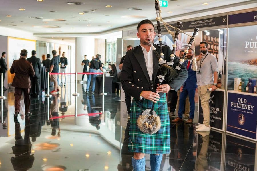 A piper in full dress at the whisky stands